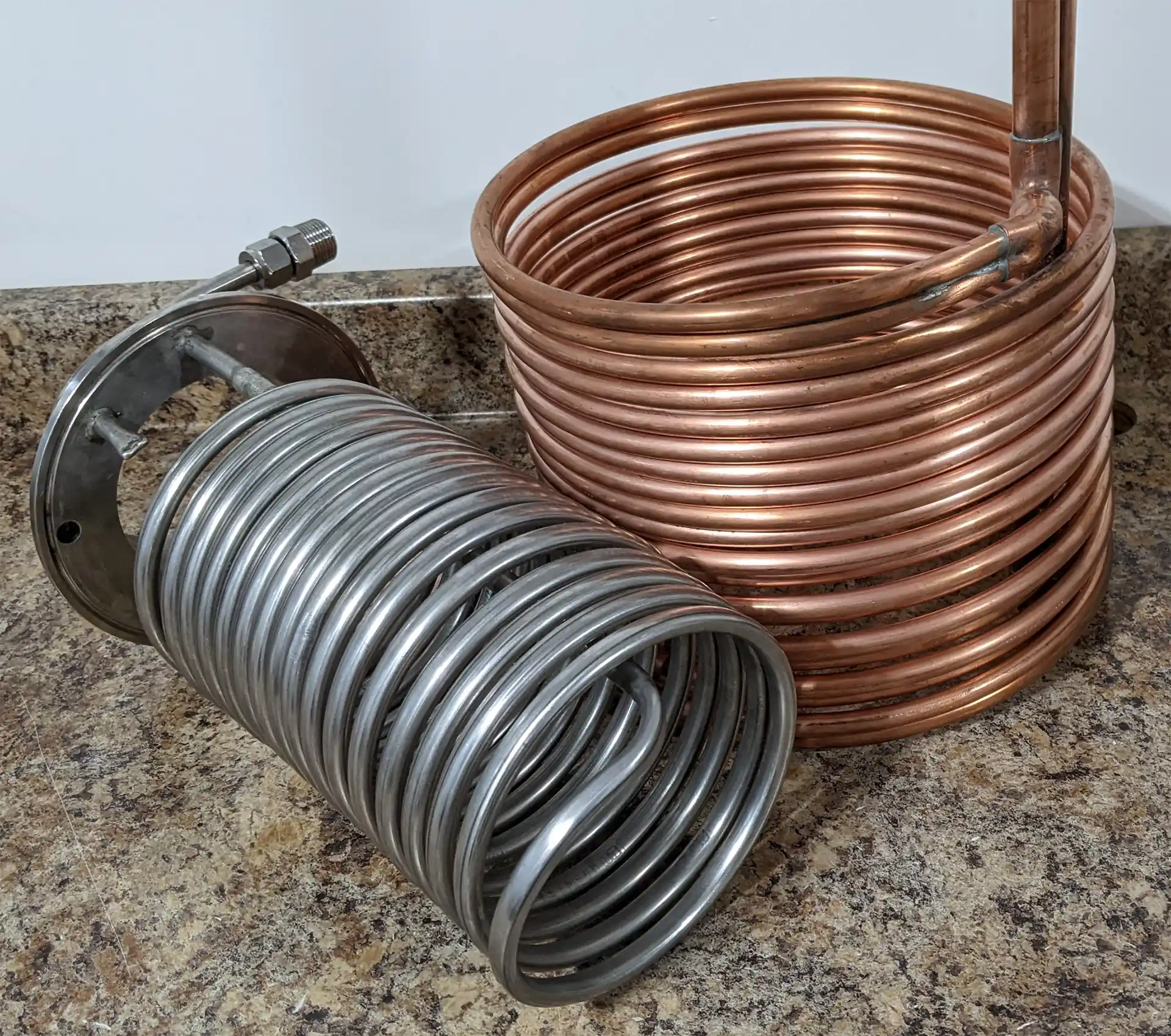 a stainless steel wort chiller next to a copper wort chiller.